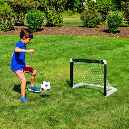 Child playing soccer with a goal on a grassy field