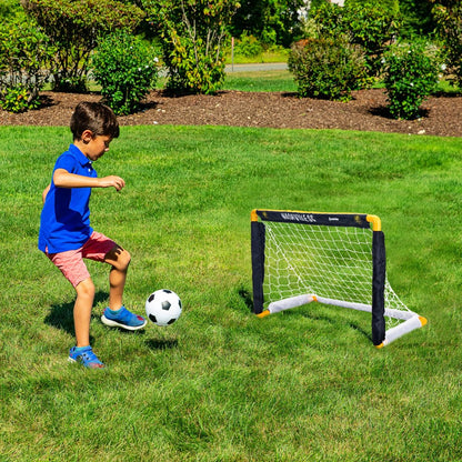 Child playing soccer with a goal and ball on a grassy field